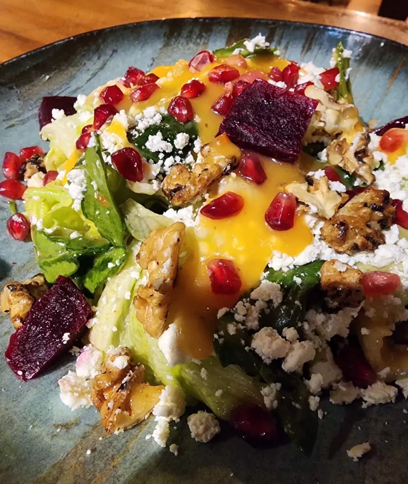 A chef salad with greens, beetroot, pomegranate, cheese and walnuts