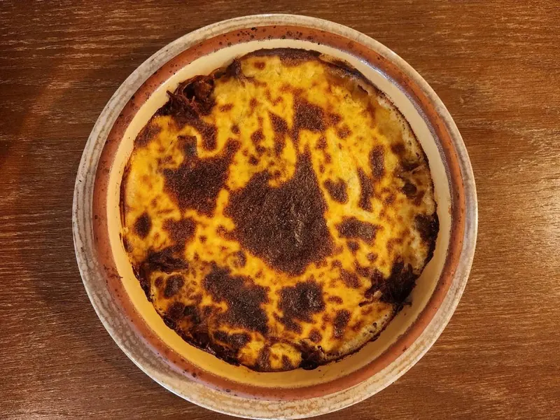 A clay dish baked golden on a wooden table