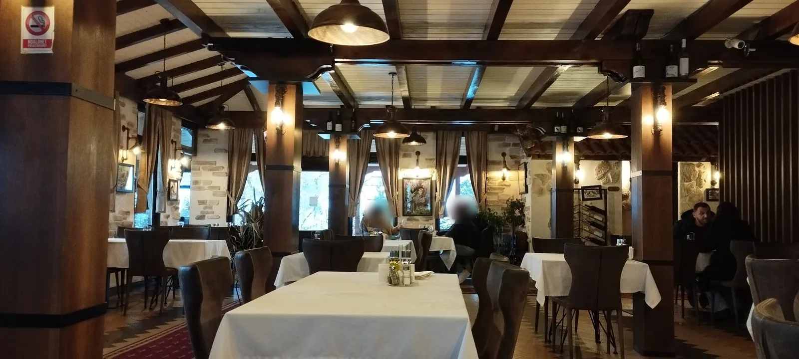 The dining room of Restaurant Bifurkacioni: wooden beams, stone pillars and tables with white cloths