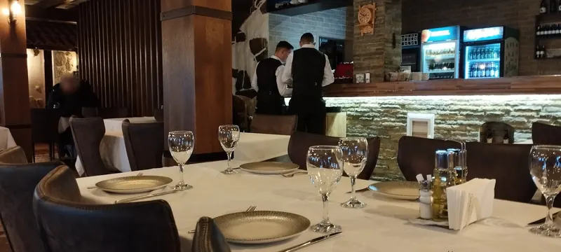 A long table set for a group inside the restaurant, with the bar and staff in the background
