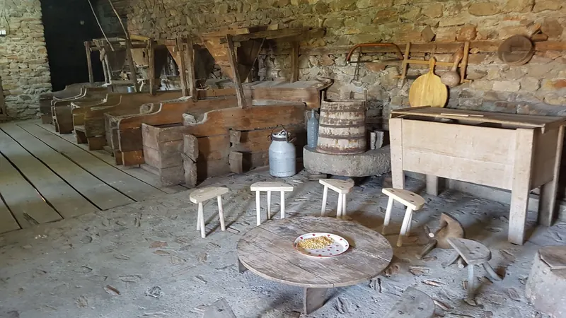A traditional corner with old wooden tools, a butter churn and low stools