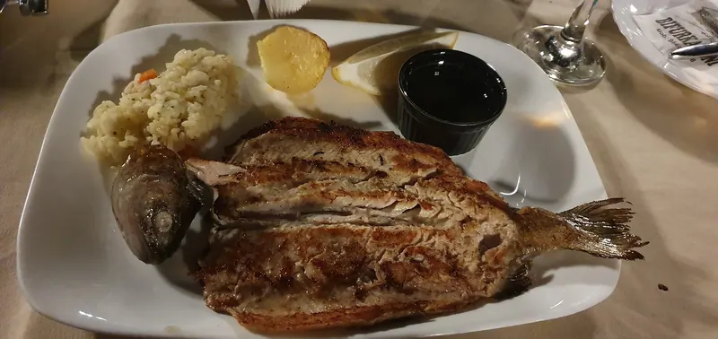 A whole grilled trout with rice and lemon